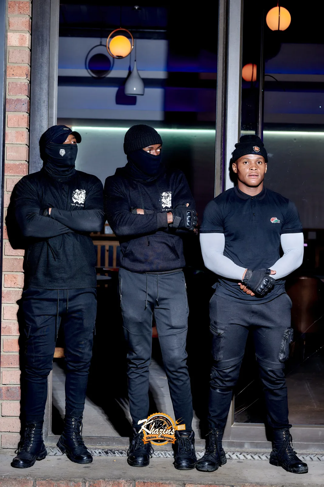 Three Bull Dogs officers in black uniform outside a lounge at night